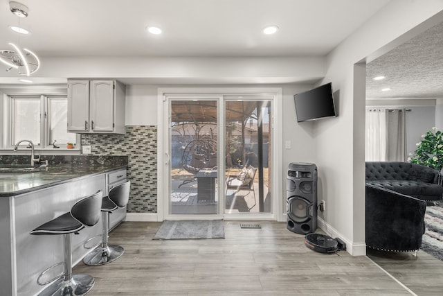 laundry room with recessed lighting, baseboards, light wood-style floors, and a sink