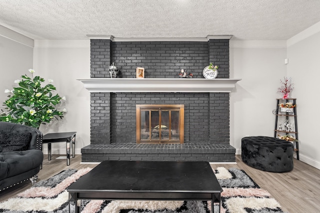 details featuring a brick fireplace, wood finished floors, baseboards, and a textured ceiling