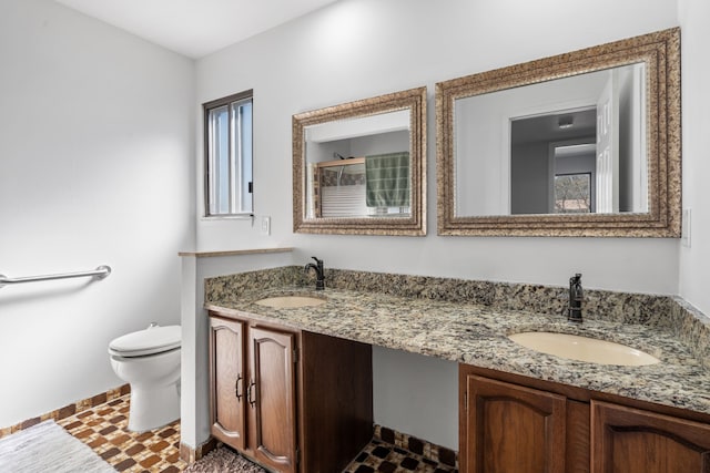 full bathroom with a sink, toilet, and double vanity