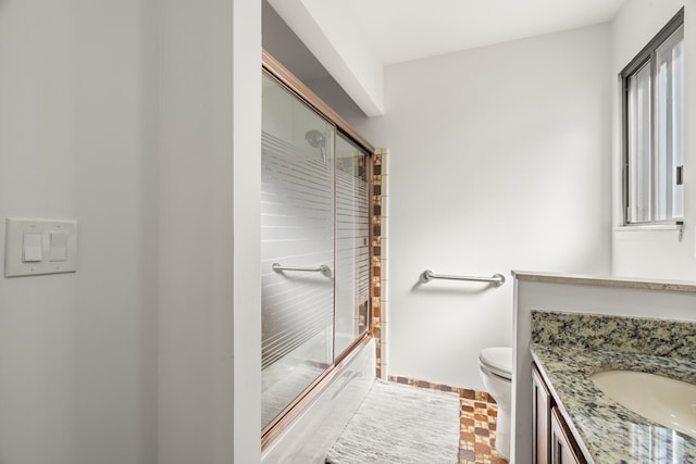 bathroom featuring shower / bath combination with glass door, toilet, and vanity