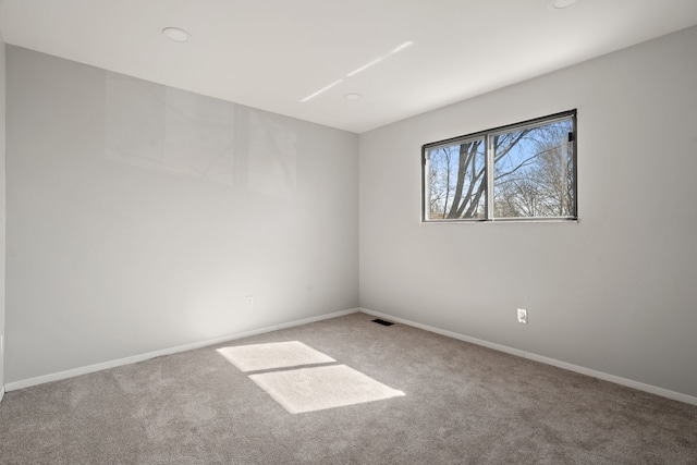carpeted spare room with visible vents and baseboards