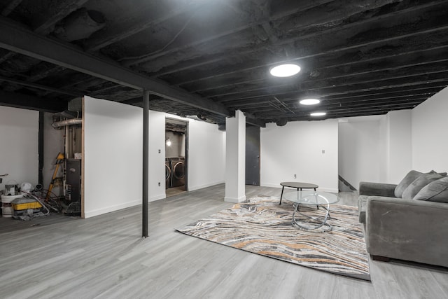 finished basement with washing machine and dryer, baseboards, and wood finished floors