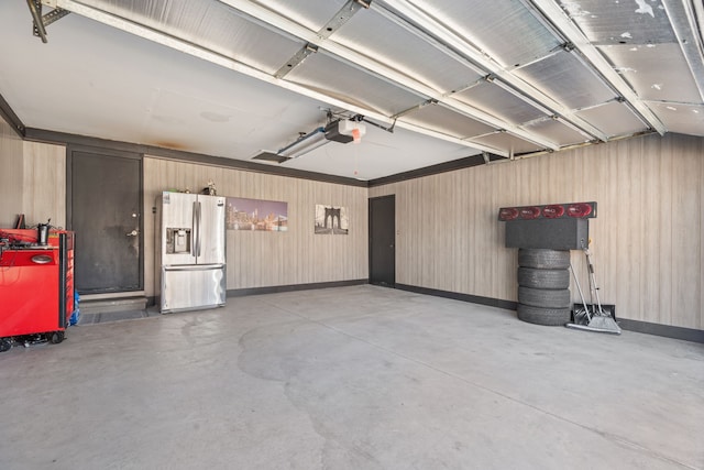 garage featuring a garage door opener and stainless steel fridge with ice dispenser