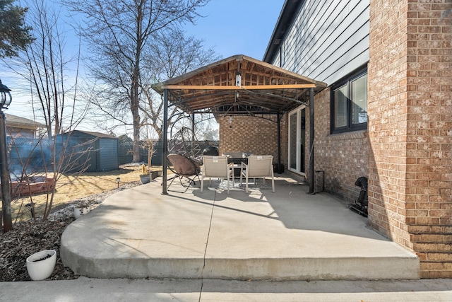 view of patio / terrace featuring fence, a shed, a gazebo, an outbuilding, and outdoor dining space