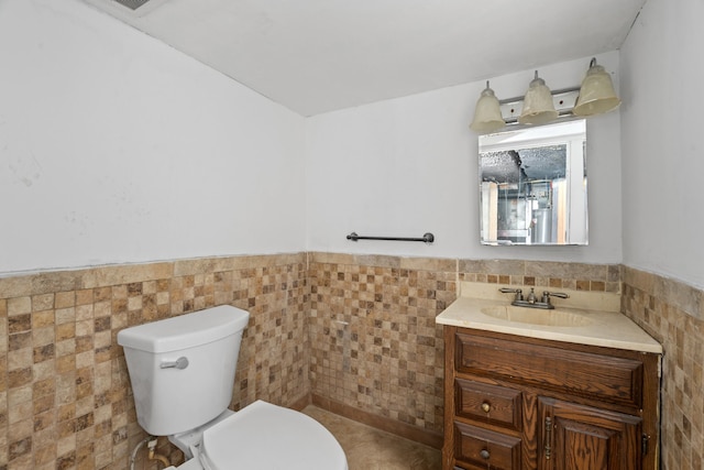 bathroom featuring vanity, tile walls, toilet, and wainscoting
