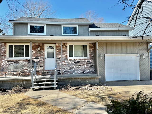 view of front of property with brick siding, a shingled roof, a porch, a garage, and driveway