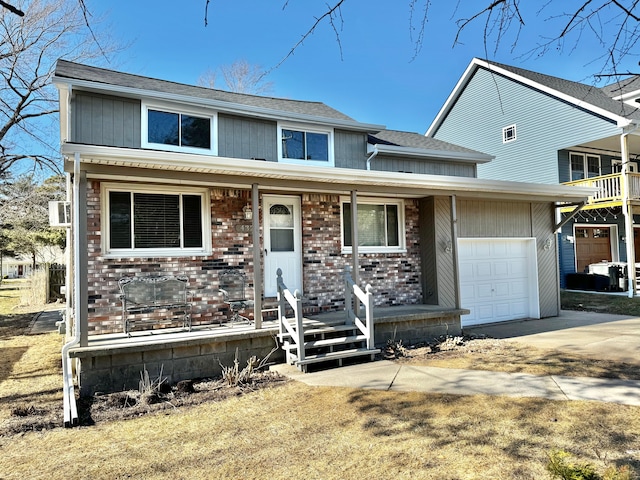 traditional home with a porch, an attached garage, brick siding, and driveway