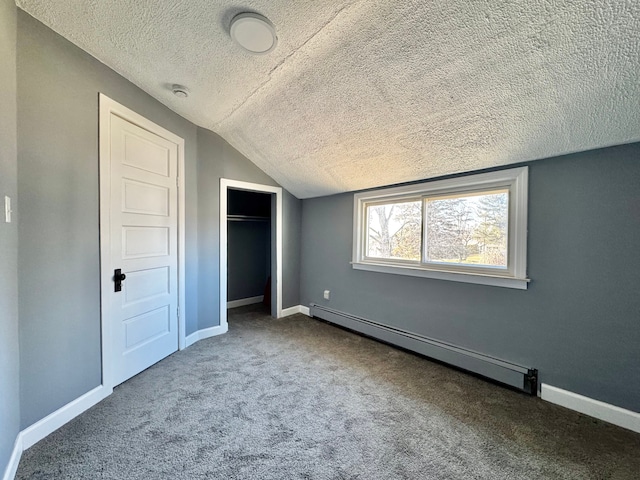 unfurnished bedroom featuring a baseboard heating unit, a closet, carpet flooring, baseboards, and vaulted ceiling