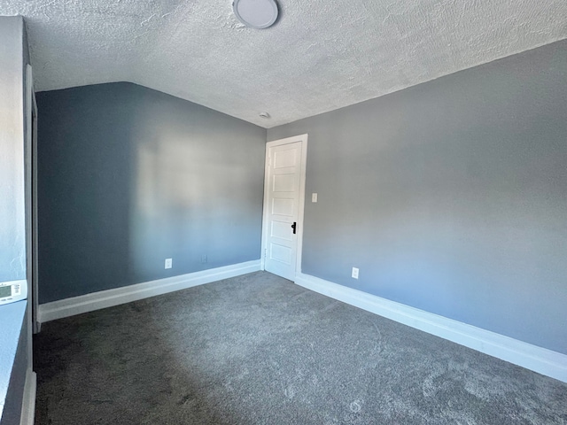 empty room featuring baseboards, carpet floors, a textured ceiling, and vaulted ceiling