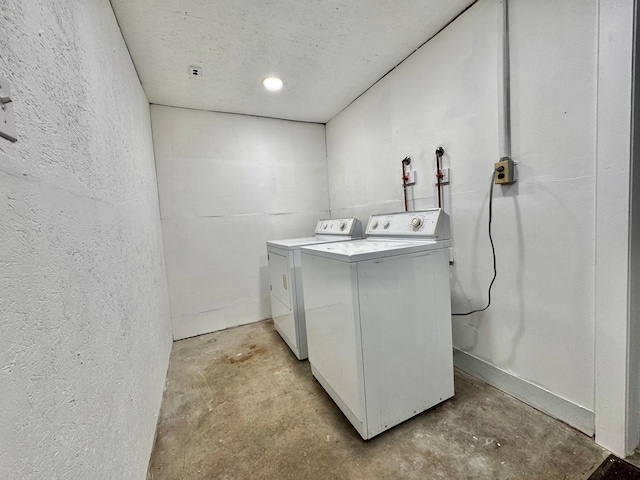 laundry room featuring a textured wall, laundry area, and washer and clothes dryer