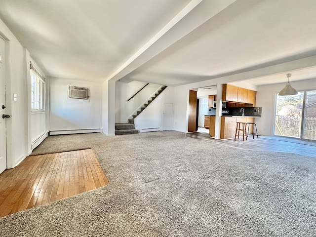 unfurnished living room featuring a wall mounted air conditioner, a baseboard heating unit, and stairs