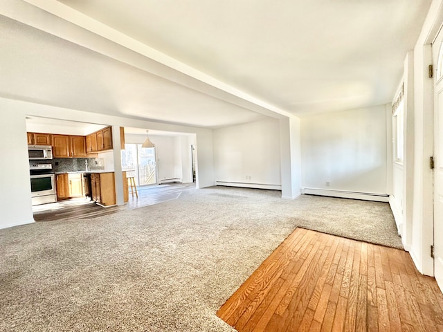 unfurnished living room featuring baseboard heating and carpet flooring