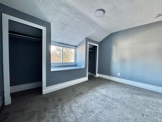 unfurnished bedroom with vaulted ceiling, a textured ceiling, baseboards, and dark colored carpet