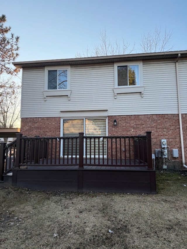 back of property featuring brick siding and a deck