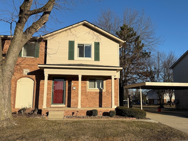 traditional home featuring brick siding, driveway, a front lawn, and a carport