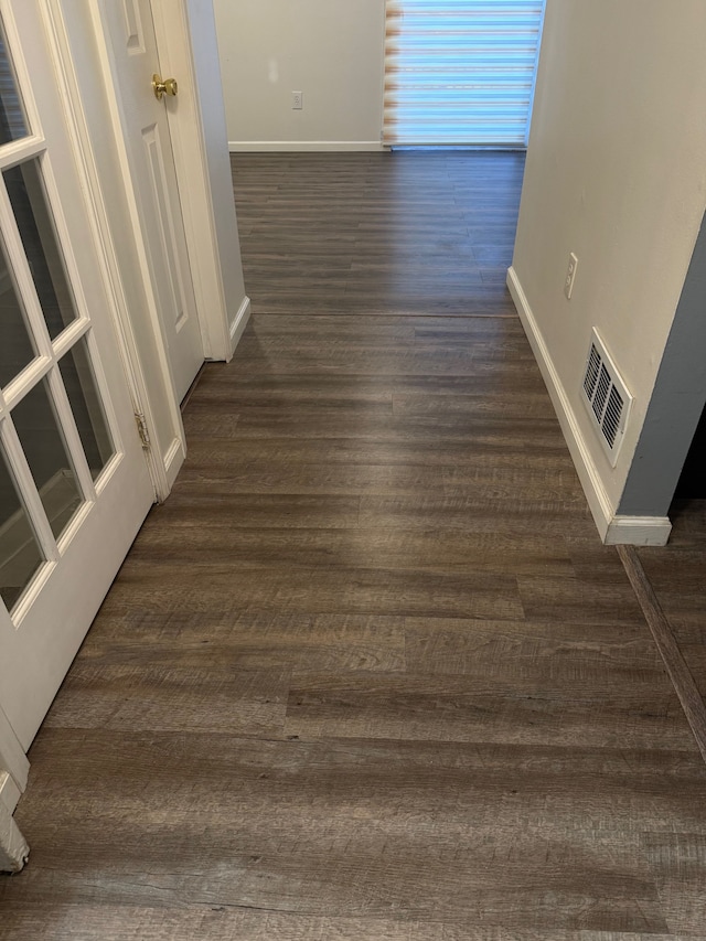 hallway featuring visible vents, baseboards, and dark wood-style flooring