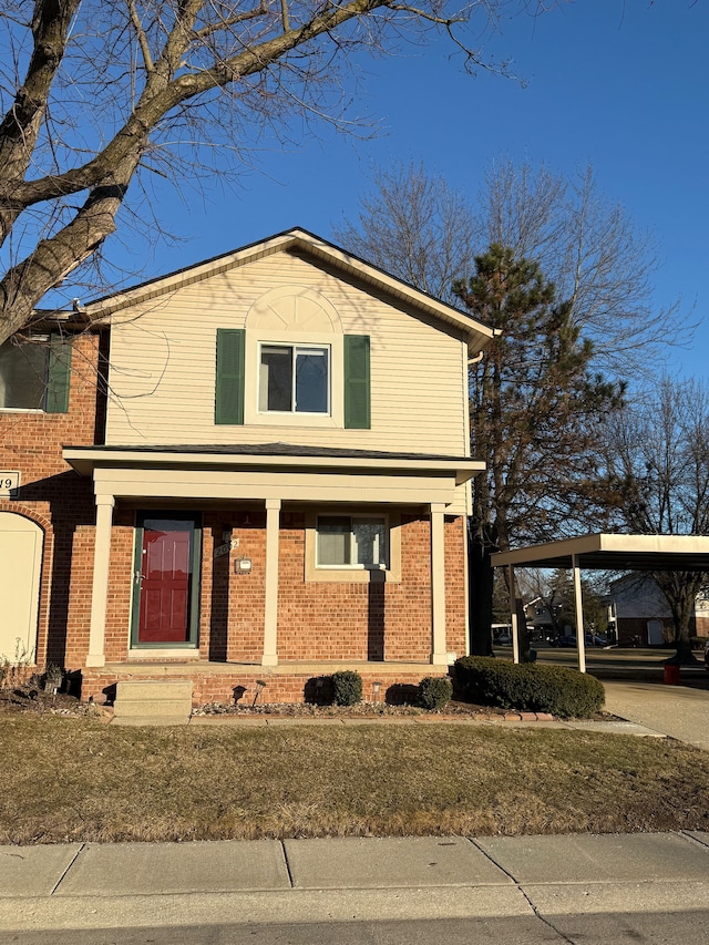 traditional-style home featuring a porch, a carport, and brick siding