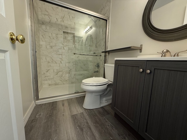 full bathroom with toilet, wood finished floors, a shower stall, baseboards, and vanity