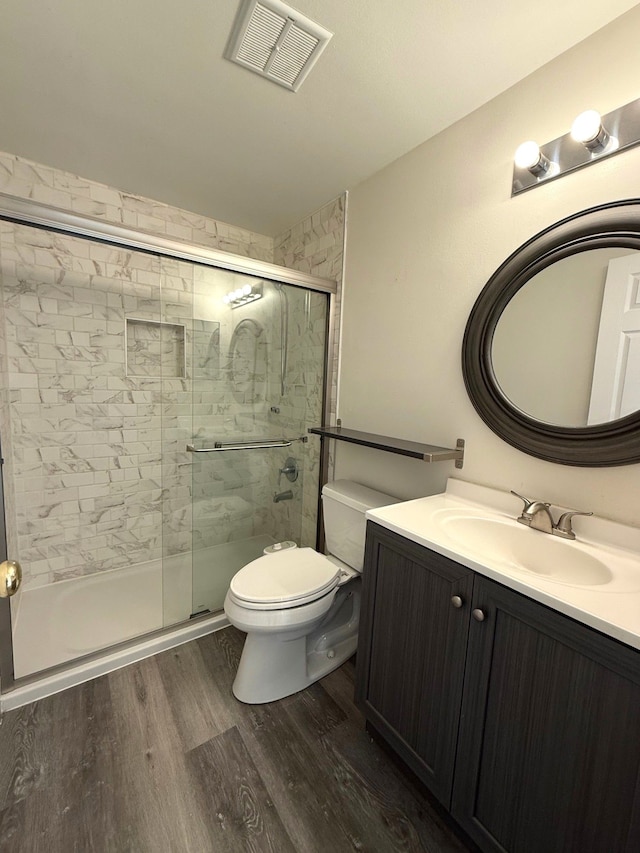 bathroom with visible vents, a stall shower, toilet, and wood finished floors