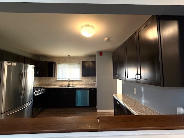 kitchen featuring dark wood-style floors, a sink, decorative backsplash, light countertops, and stainless steel appliances