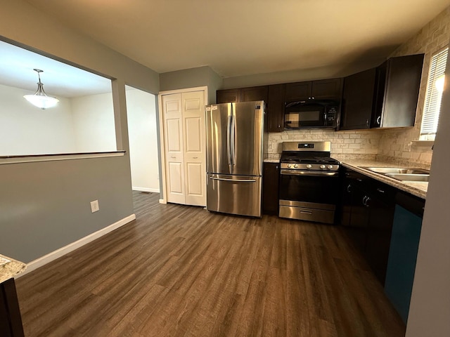 kitchen featuring light countertops, decorative backsplash, appliances with stainless steel finishes, dark wood-style floors, and a sink