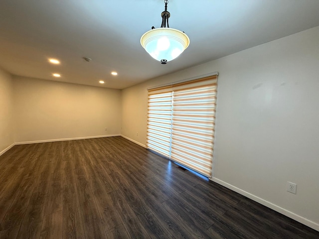 empty room with dark wood-type flooring, recessed lighting, visible vents, and baseboards