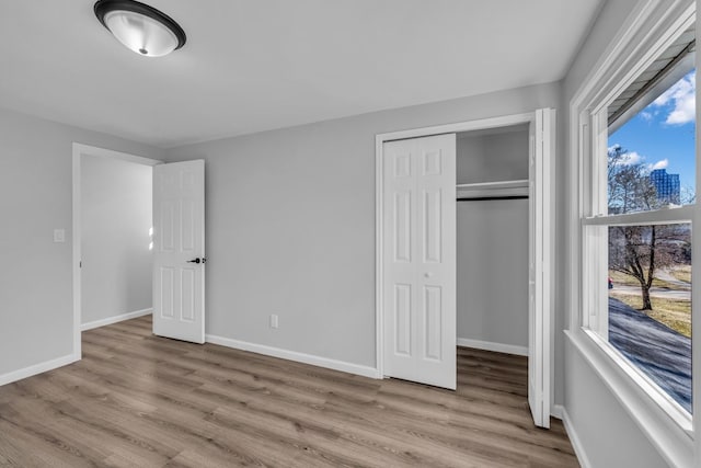 unfurnished bedroom featuring a closet, baseboards, and wood finished floors