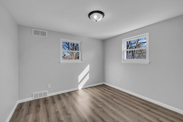 spare room featuring visible vents, baseboards, and wood finished floors