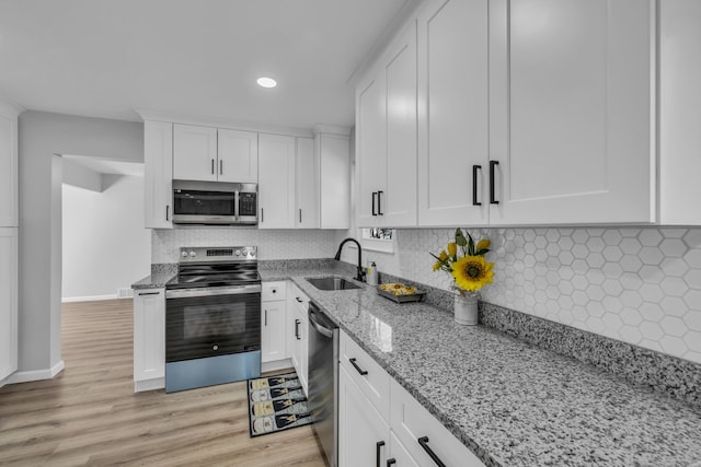 kitchen with tasteful backsplash, light stone counters, appliances with stainless steel finishes, white cabinetry, and a sink