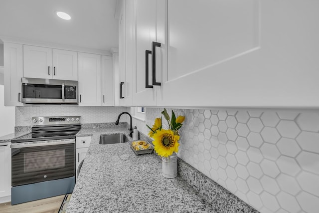 kitchen featuring a sink, light stone countertops, appliances with stainless steel finishes, and white cabinets