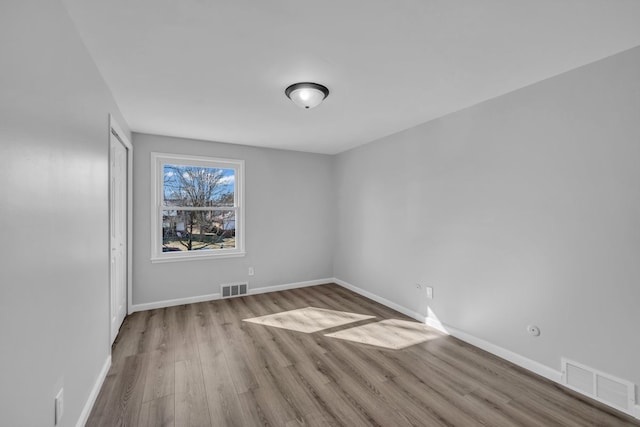 empty room with visible vents, baseboards, and wood finished floors