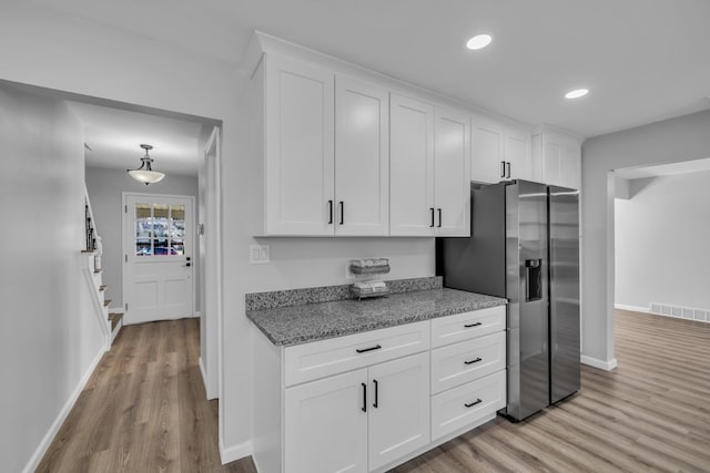 kitchen with light wood-type flooring, visible vents, stainless steel refrigerator with ice dispenser, white cabinetry, and recessed lighting