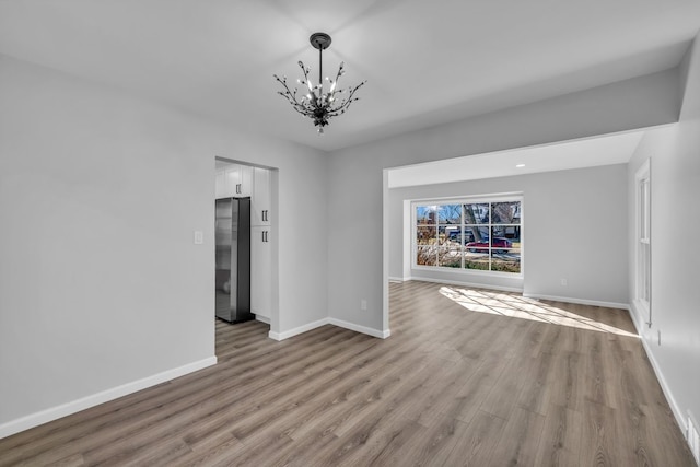 interior space featuring an inviting chandelier, wood finished floors, and baseboards