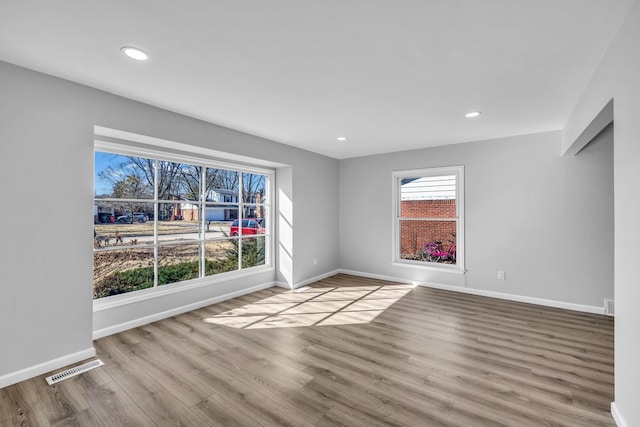 empty room featuring recessed lighting, visible vents, baseboards, and wood finished floors