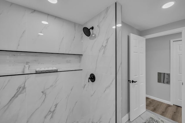 details with wood finished floors, baseboards, and a marble finish shower