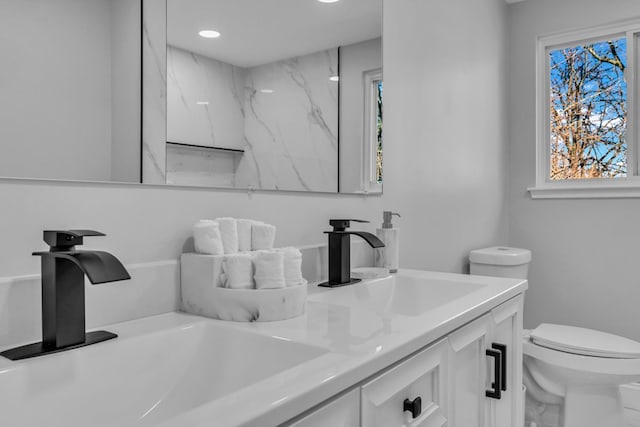 bathroom with double vanity, toilet, and a sink