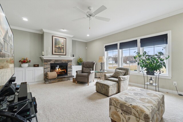 living room with baseboards, ceiling fan, a stone fireplace, ornamental molding, and light colored carpet