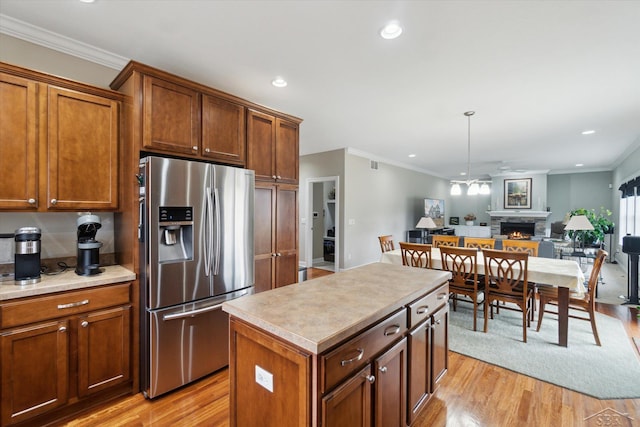 kitchen featuring a fireplace, open floor plan, light wood-style flooring, and stainless steel refrigerator with ice dispenser