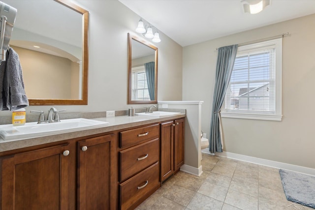 full bath featuring double vanity, toilet, baseboards, and a sink