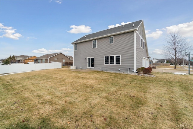 rear view of house featuring a lawn and fence