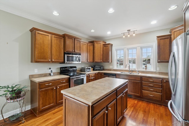 kitchen with light wood finished floors, a sink, appliances with stainless steel finishes, brown cabinetry, and crown molding