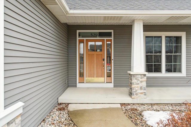 view of exterior entry featuring a shingled roof