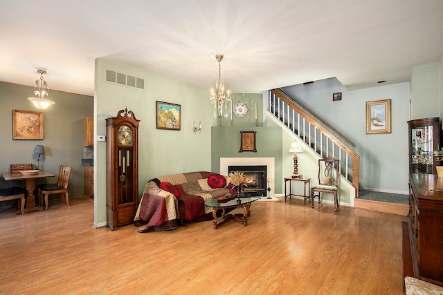 living area with visible vents, a warm lit fireplace, light wood-style floors, baseboards, and stairs