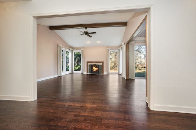 unfurnished living room with dark wood-style flooring, vaulted ceiling with beams, baseboards, and a warm lit fireplace