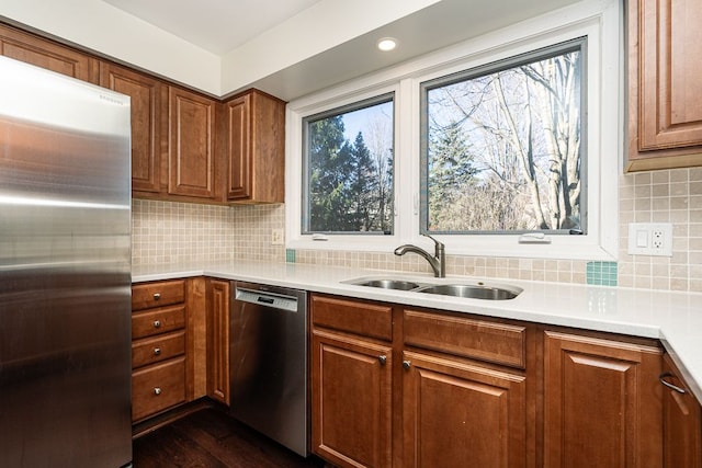 kitchen with a sink, stainless steel appliances, decorative backsplash, and brown cabinetry