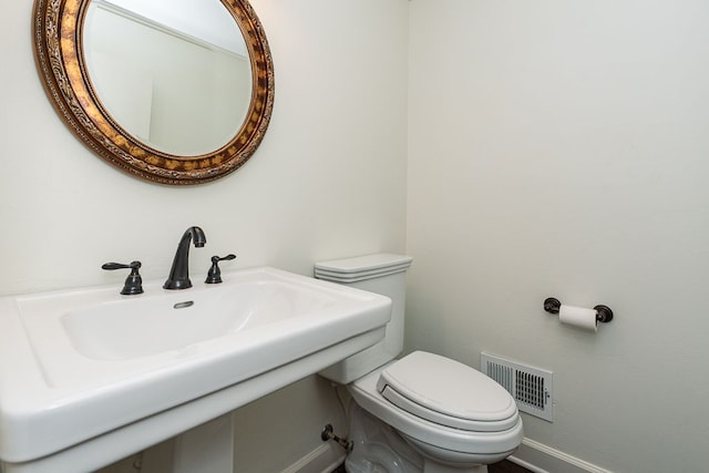 bathroom featuring a sink, visible vents, baseboards, and toilet