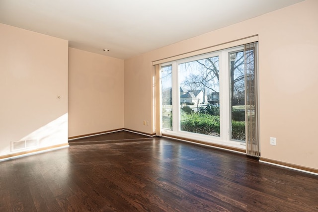 empty room featuring visible vents, wood finished floors, and baseboards