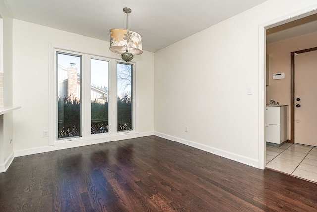 unfurnished dining area with a chandelier, baseboards, and wood finished floors