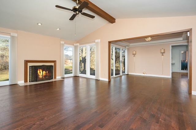 unfurnished living room with a wealth of natural light, dark wood-style floors, vaulted ceiling with beams, and a fireplace with flush hearth