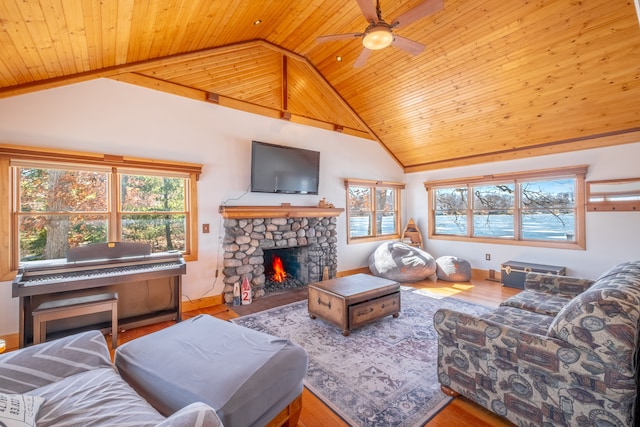 living area featuring a wealth of natural light, wood ceiling, wood finished floors, and a stone fireplace